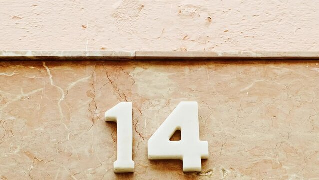 Number 14 (fourteen) affixed to the exterior of a building, with an elegant, vintage and traditional appearance