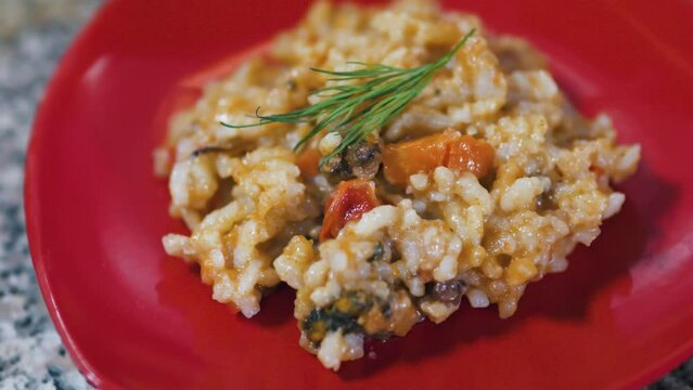 Spanish seafood paella risotto on a red plate. Close up.