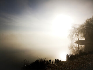 On a foggy winter morning, the big fog over the lake, a fisherman on the small peninsula