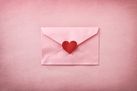 Closed pink envelope with heart cutout on pink textured background