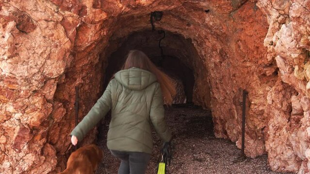 Person and Dog venture into a rocky tunnel. Travel in Montenegro.