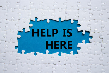 Help is here symbol. Concept words Help is here on white puzzle. Beautiful blue background. Business and Help is here concept. Copy space.