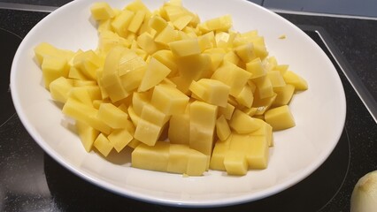 Potatoes have been peeled and cut then put its  into a white plate.