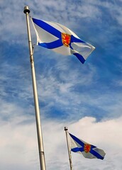 The pair of provincial flags of Nova Scotia waving in the wind against a bright blue sky