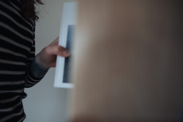 A young woman reaches into a shelf to pull out or put back a photo book. No face is visible.
