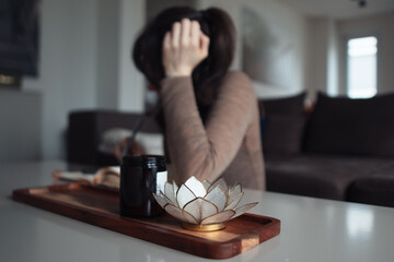A young woman sitting at a coffee table and writing in a journal. No face is visible. - obrazy, fototapety, plakaty