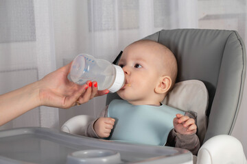 Complementary feeding of the baby with milk formula that replaces breast milk. Close-up
