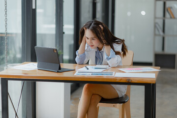 Asian businesswoman working on tablet with documents and stressed over worked from work in the office, Tired and Overworked businesswoman concept.