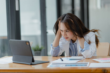 Asian businesswoman working on tablet with documents and stressed over worked from work in the office, Tired and Overworked businesswoman concept.