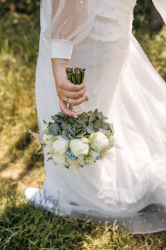 Wedding bouquet close-up photo. The bride in a white dress holds beautiful flowers in her hands