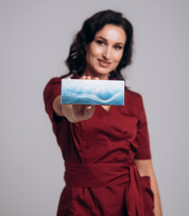 Cosmetologist beautician holds a package with drugs for facial rejuvenation. A female doctor in office shows treatment options. Mockup with copy space