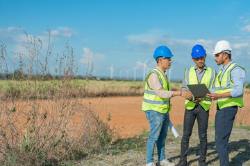 Asian engineers working in fieldwork outdoor. Workers walking and inspect construction and machine around project site. Wind turbine electrical of clean resource enerdy and environment sustainable.