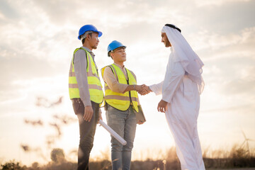 Asian Engineers and Arab businessman checking and inspecting on construction with sunset sky....