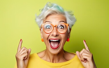 Funny elderly woman with silly expression makes gestures, happily and feels proud of her success, smiles gladfully