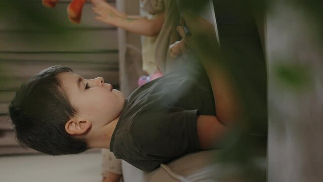 Adorable boy, sitting on the sofa writing homework at home. Kid learing and writing alphabet.