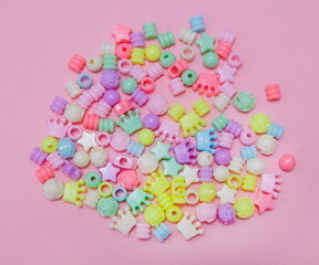 Top view of multi-colored beads on pink background