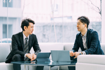 パソコンとタブレットを使って打ち合わせをする2人の男性ビジネスマン