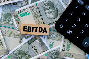 Fototapeta premium EBITDA text on wooden cube with calculation and currency