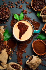 A cup of aromatic fragrant coffee with an image of South America. Set of coffee beans and ground coffee in the shape of a world map
