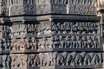 Intricate carvings of a line of elephants, lions and an army of horses on the wall of the ancient Chennakashava temple in Belur in Karnataka.