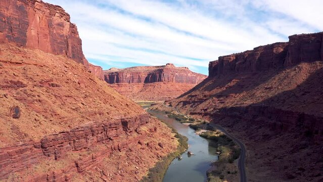 Colorado river flowing in red rock massif of brick structure in canyon is destroyed by soil erosion and weathered. Western Usa in Utah, near moab and arches national park. Curve road along shore