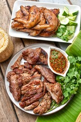 Grilled pork with wings  and chili sauce with vegetables, top view food , banana leaf and blur background,thai food