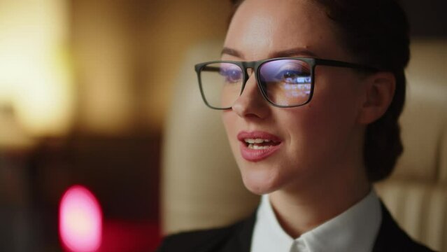 A young business assistant girl looking some videos in glasses reflection. Cheerful woman in office browsing content in internet. Smm manager scrolling website with photos and videos she could buy 