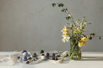 Happy Easter! Stylish easter eggs and spring flowers bouquet on rustic wooden table in rural room....