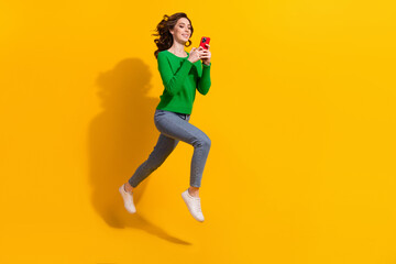 Fototapeta na wymiar Full body length photo of jumping trampoline running with smartphone cant stop using her device isolated on yellow color background