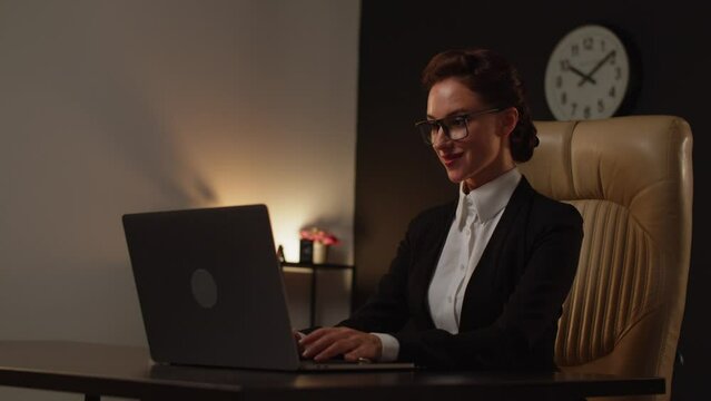 A young woman positive boss sitting on comfortable leather chair in office and using notebook. It specialist lady senior level programmer. Business analytic woman using computer. No paperwork, just