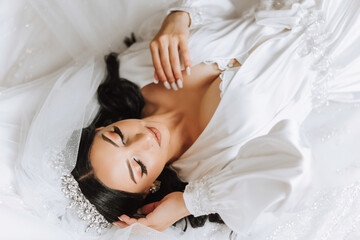 A beautiful young bride girl is lying in a beautiful robe. Morning of the bride before the wedding ceremony.