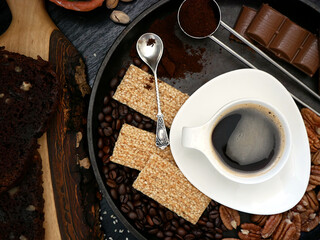 Black espresso coffee, cookies with sesame seeds and chocolate.