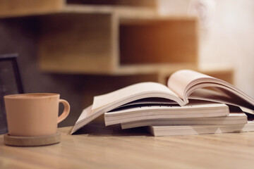 Close up stack of magazine or books with cup of coffee on wooden table in copy space concept. - Powered by Adobe