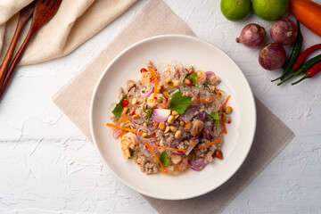 Spicy Glass Seaweed noodle Salad with Minced Pork (yum sen kaew) is a type of Thai salad made with clear Kelp noodle and meat in white plate.Top view © Kritchai