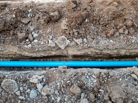 The new PVC pipe is laying in the trench.