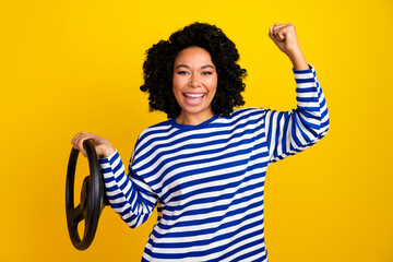Portrait of ecstatic girl with afro hairstyle hold steering wheel scream yeah win new car in lottery isolated on yellow color background
