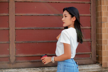 Teenage girl dressed in vintage clothes Including a white t-shirt and pants. Stand facing a wall and pose.