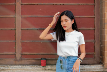 Teenage girl dressed in vintage clothes Including a white t-shirt and pants. standing behind the wall smiling