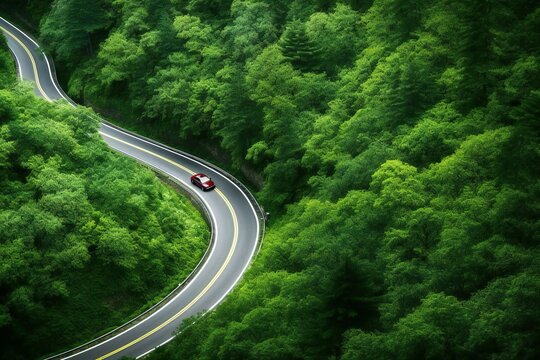 Aerial view of winding mountain road with red car in green forest © Harmonic