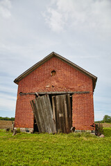 Weathered Brick Barn with Decaying Doors in Countryside