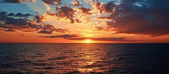 Fototapeta premium As the radiant sun descended towards the horizon, casting hues of orange and pink across the vast expanse of the sea.