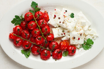 baked cherry tomatoes , with cheese, and spices, on a white plate, homemade, no people,
