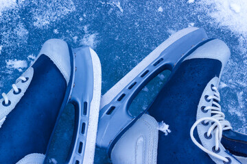 The pair of ice skates on frozen surface of pond or lake. Outdoor winter activity equipment. - 719341307