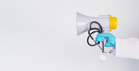 Doctor's hand wear latex glove and hold Megaphone and stethoscope on white background.
