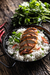 Grilled chicken breast served in a pan with jasmine rice and chili peppers