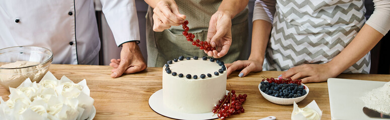 cropped view of mature woman decorating cake with red currant near chef and her young friend, banner