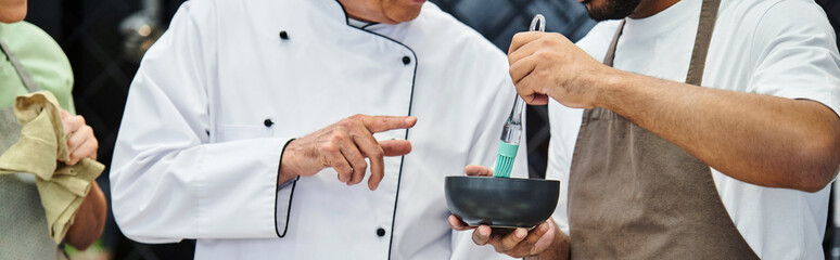 cropped view of african american man brushing cake with syrup next to chef and his friends, banner
