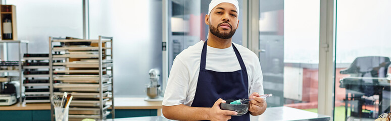 handsome african american chef in toque looking at camera while on kitchen, confectionery, banner
