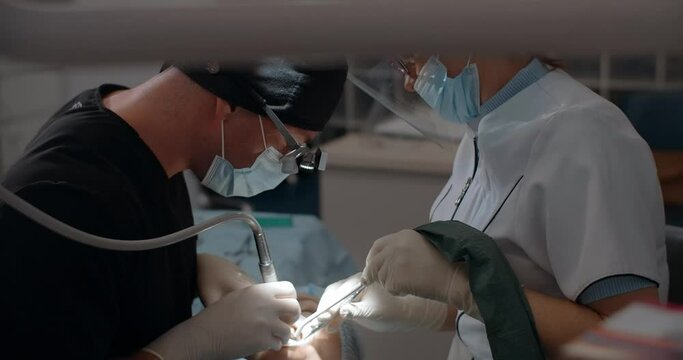 The dental surgeon does the surgery with assistant in dental clinic