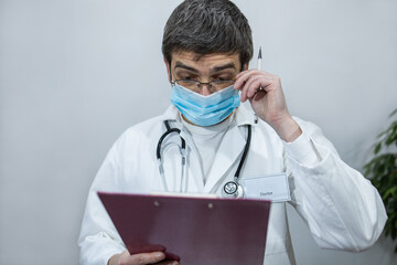 Doctor writing on clipboard. Doctor with mask and stethoscope. Portrait of a doctor 